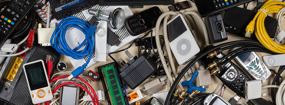 © mrallen / stock.adobe.com Ansammlung verschiedenster elektronischer Geräte und Kabel, darunter Mobiltelefone, Fernbedienungen und Netzwerkkabel.